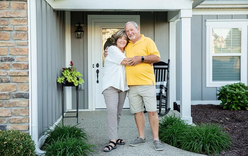 Happy Couple Standing in Front of Their House With New Siding